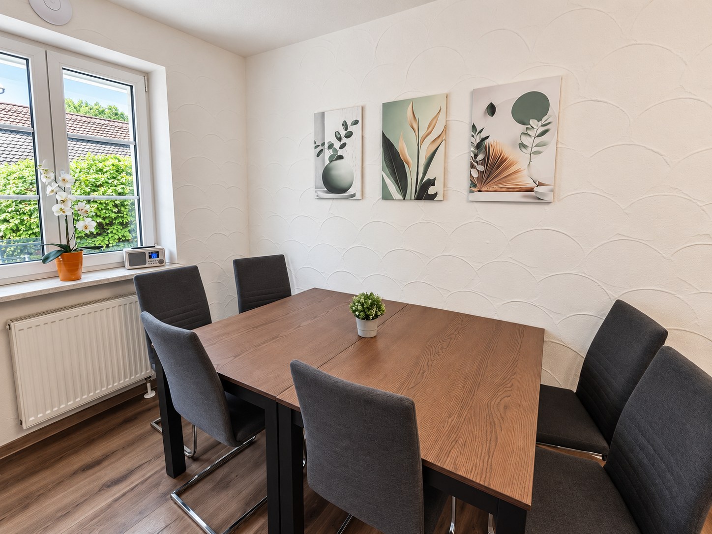 Essbereich mit Holztisch und sechs grauen Stühlen