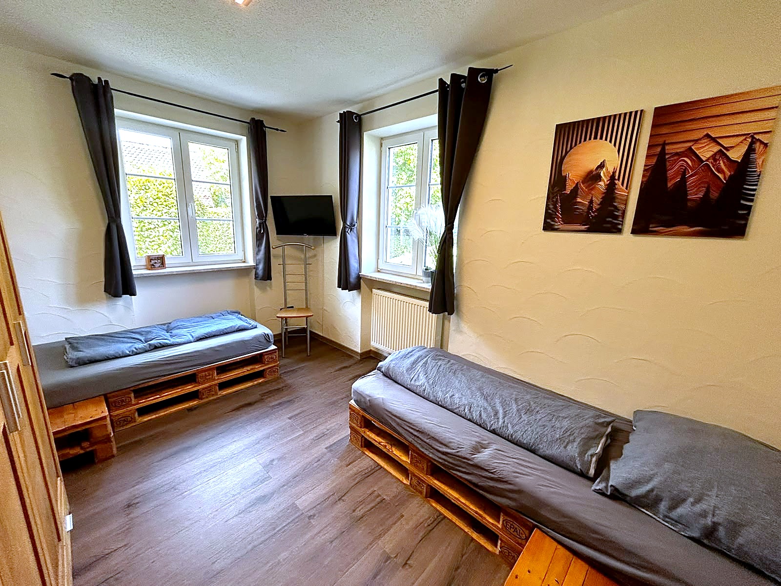 Schlafzimmer mit zwei Betten, Fernseher und Blick in den Garten